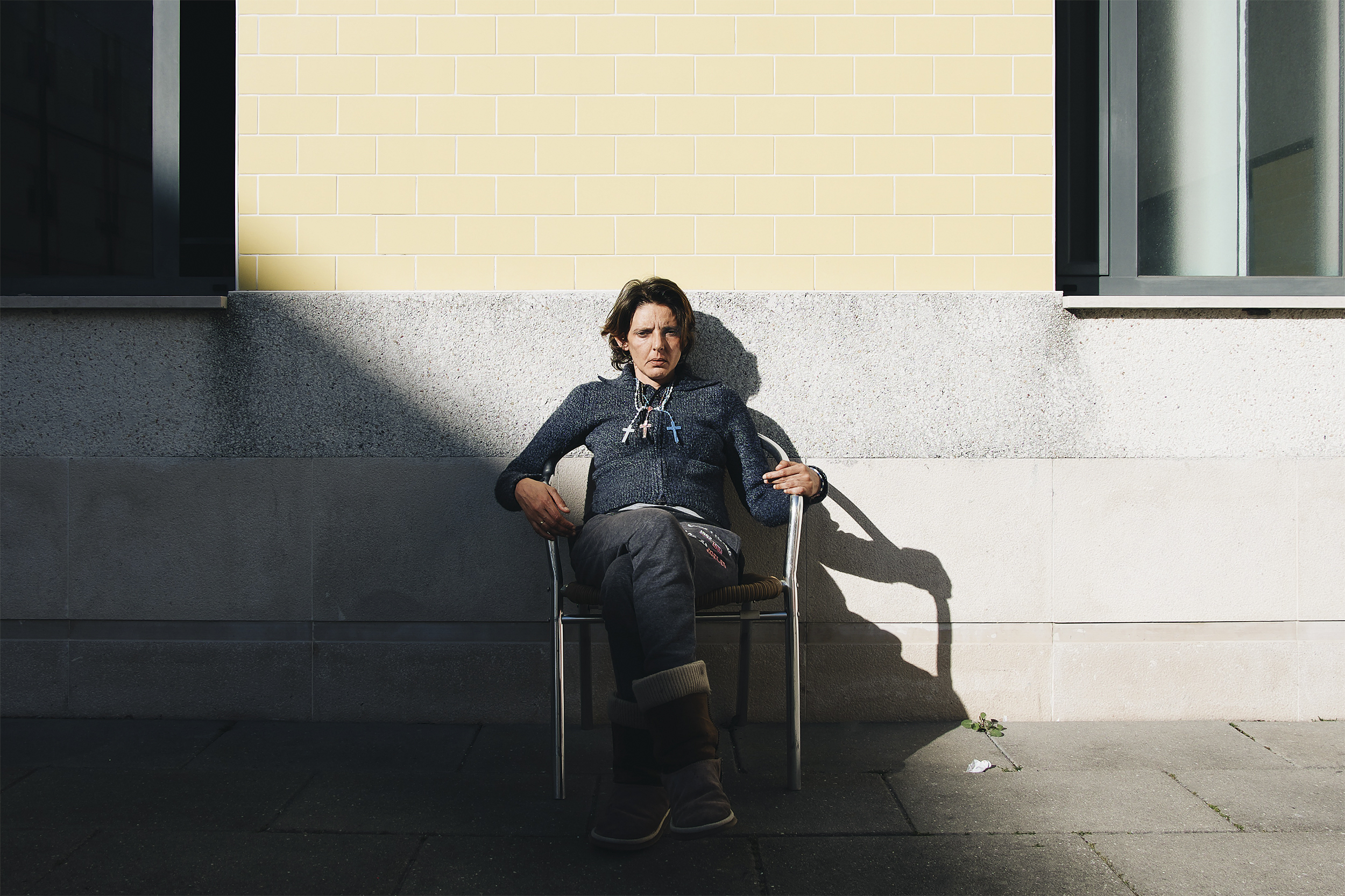 Mulher de olhos fechados, encostada a parede onde se lê o seu nome.