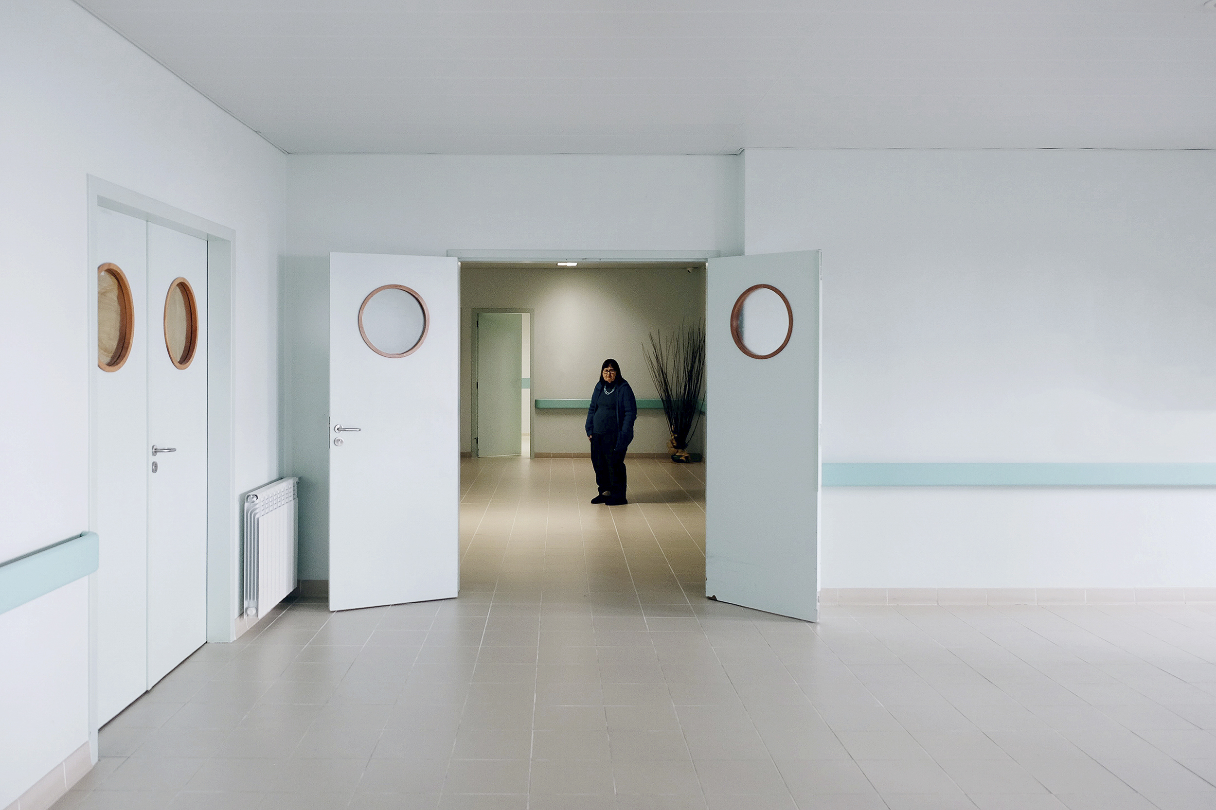 Mulher em pé ao longe num espaço arejado e azul claro.