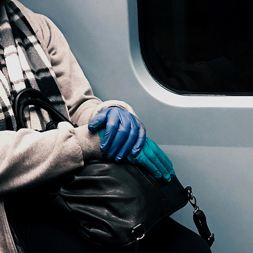 Mãos cruzadas. Mão esquerda com luva de látex azul, mão direita com luva de látex verde.