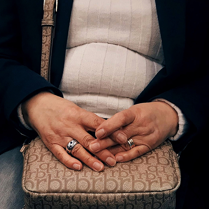 Mãos de mulher entrelaçadas em cima de uma mala.