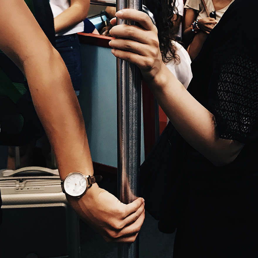 Duas mulheres agarram poste vertical do metro.