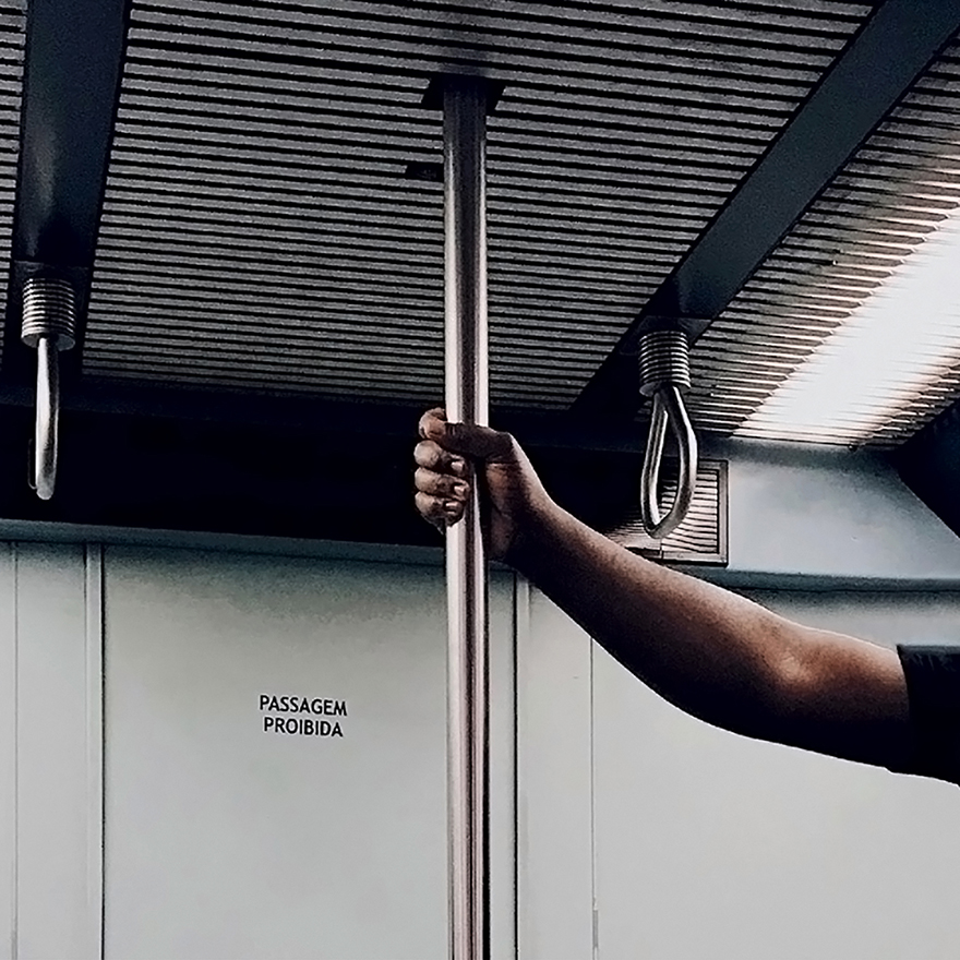 Mão agarra poste vertical do metro.