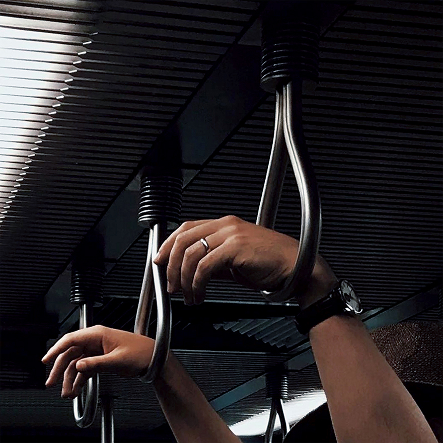 Mãos suspensas em pegas metálicas do metro.